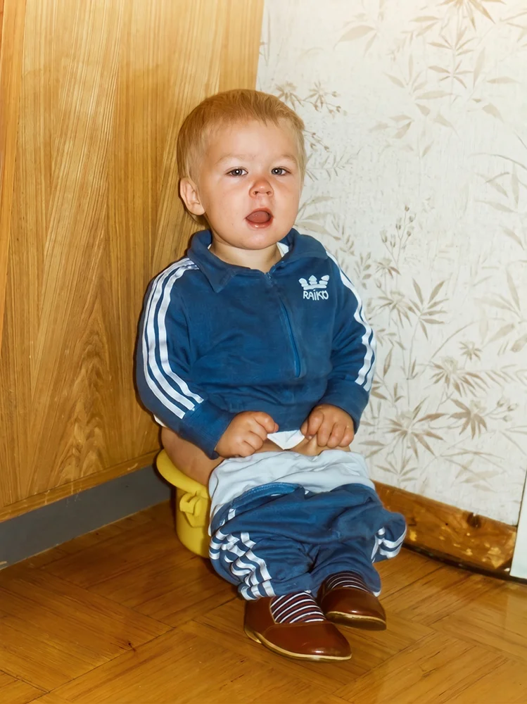 Taastatud vana foto sinises dressis väikelapsest potil istumas.