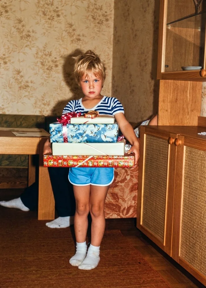 Taastatud vana foto lapsest toas kingipakke hoidmas.
